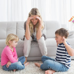 Fed up mother listening to her young children fight at home in the living room