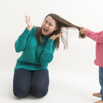 A little girl pulls her older sister hair